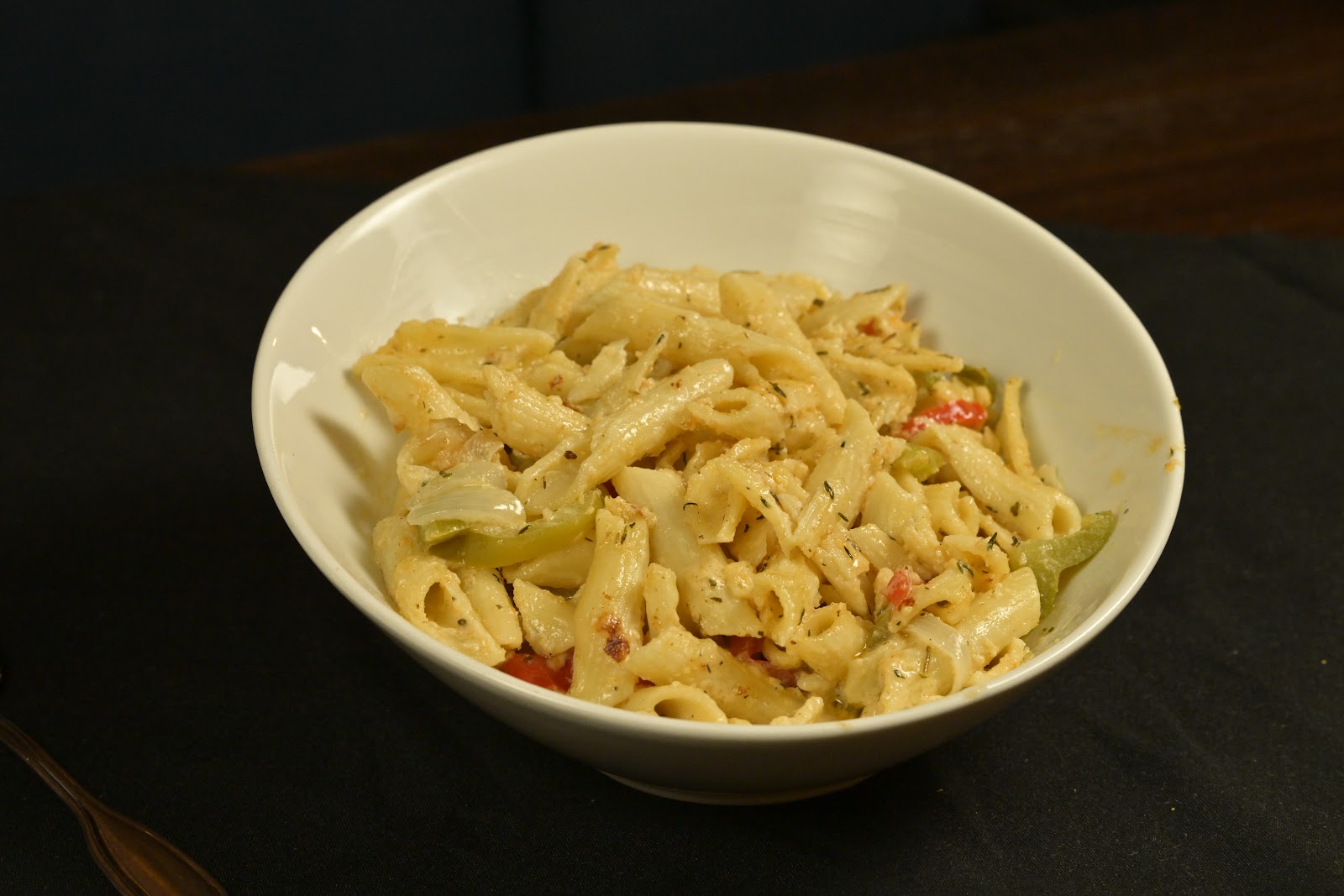 Creamy penne pasta with peppers in a white bowl